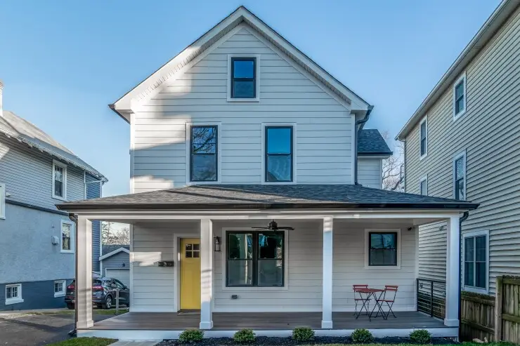 Simple single family home with large covered porch supported by four columns, yellow decorative door